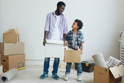 Father, son carrying moving boxes
